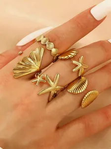 Close-up of gold stainless steel starfish and seashell adjustable rings worn on hand