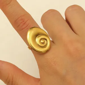 Macro view of a golden spiral snail shell design adjustable ring on a finger