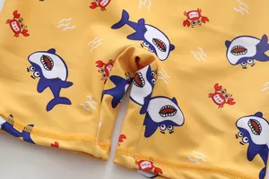Makroaufnahme von gelbem Kinder-Badebekleidungsstoff mit Hai- und Krabbenmotiven