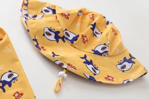 Detail eines gelben Sonnenhutes mit Cartoon-Hai- und Krabbenmotiven