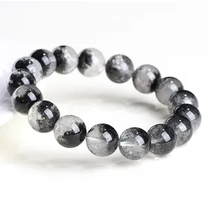 Detalle en primer plano de pulsera de cuarzo rutilado negro natural con cuentas efecto cuenco