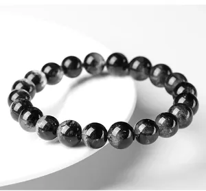 Primer plano de una pulsera de cuarzo rutilado negro natural con agujas visibles.