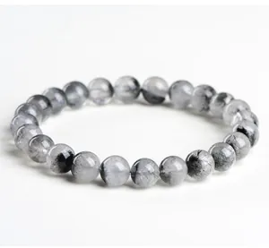 Primer plano de pulsera de cuarzo rutilado negro natural con inclusiones de cristal.