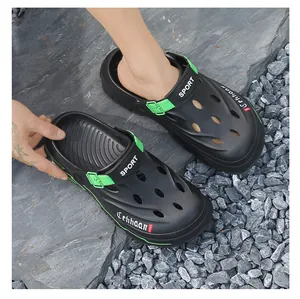 High angle view of black and green breathable outdoor clogs for men on rocky surface