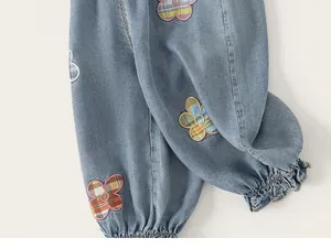 Detalle de vaqueros azul claro para niña con parches florales y puños elásticos