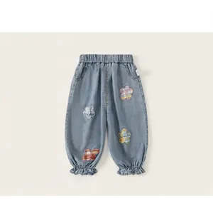 Vista frontal de pantalones vaqueros anchos para niñas en azul claro con apliques de flores.