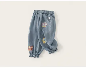 Detalle de vaqueros azul claro para niña con parches florales de colores y puños con volantes