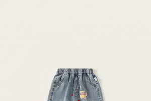 Primer plano de pantalones vaqueros infantiles con bordados florales y cintura elástica.