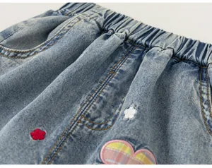 Primer plano de vaqueros para niña con cintura elástica y bordados de flores y corazones