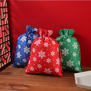 Details of red, blue, and green burlap Christmas gift bags with white snowflake patterns