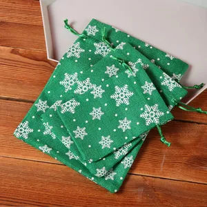 Macro detail of green faux linen Christmas gift bags with white snowflake patterns