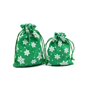 Detail of green faux linen Christmas gift bags with white snowflake pattern and drawstring.