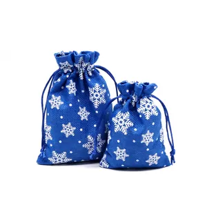 Detail view of blue Christmas drawstring burlap gift bags with white snowflake patterns.