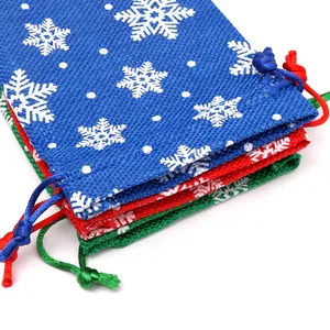 Close-up of Christmas burlap gift bags with snowflake patterns and drawstring closure.