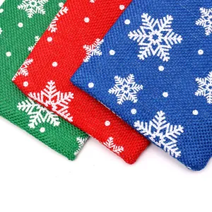 Detail view of Christmas linen gift bags with snowflake patterns in red, green, and blue.