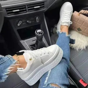 Eleganti sneakers platform bianche da donna abbinate a jeans in denim blu strappati