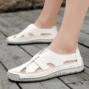 White handmade stitched summer hollow sandals for breathable casual beach wear on wood plank