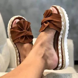 Detail view of women's brown bow-knot platform sandals with braided jute wedge soles