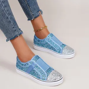 Macro view of blue and silver sequin slip-on sneakers for women on model wearing jeans