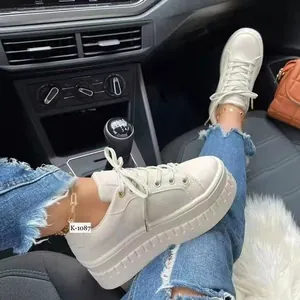 Primo piano di sneakers beige con zeppa da donna indossate in un'auto moderna
