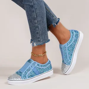 Close-up view of women's blue and silver glitter slip-on sneakers worn by a model
