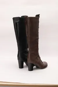 Detail view of black and brown knee-high boots with stud accents and chunky heels.