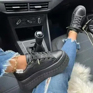 Close-up lifestyle view of stylish women's black platform sneakers worn inside a car