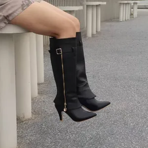 Gros plan sur des bottes noires pointues à talons aiguilles avec fermeture éclair dorée