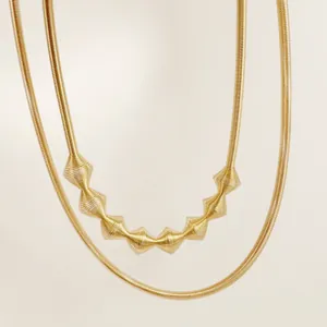 Close-up view of a gold geometric metal collar necklace featuring textured snake chain design.