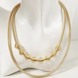 Detailed view of bold gold metallic geometric choker necklace with ridged spiral design