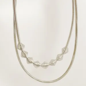 Detail of a minimalist silver metallic necklace with geometric sculptural elements