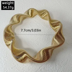 Detail of a chunky gold wavy metal choker necklace with a 7.7cm diameter dimension.