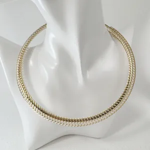 Close-up of a gold-toned ribbed metal choker necklace on a white jewelry mannequin