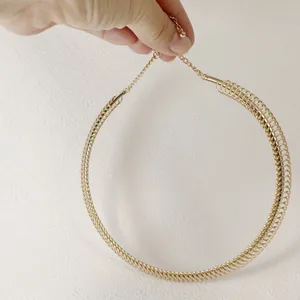 Close-up of golden coiled metal choker necklace with adjustable chain and bead