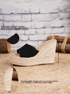 Detalle de sandalias de cuña de paja negra con tacón de 11,5 cm y una textura muy suave.