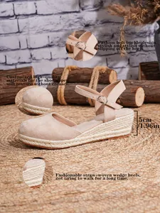 Detalle de sandalia de cuña de esparto beige con suela trenzada y hebilla lateral.