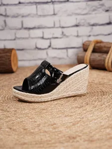 Detail view of black crocodile-textured espadrille wedge sandals with buckle strap.