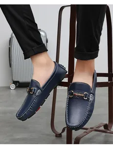 Detail view of navy blue leather loafers with metal buckle and white stitching on model