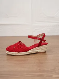 Detalle lateral de sandalia roja con cuña de ganchillo y suela de yute trenzado