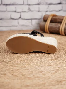 Detailed view of the sole on black espadrille wedge sandals with woven jute platform