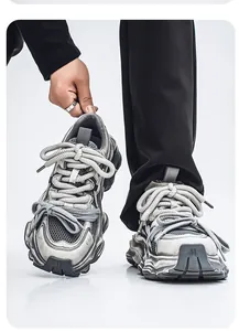 Primo piano di sneakers chunky grigie distressed con lacci in corda e inserti in mesh.