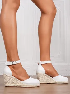 White wedge espadrilles with ankle strap shown from a side angle on a wooden floor.