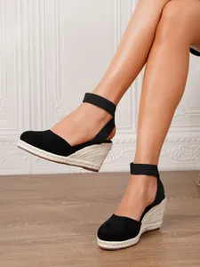 Primer plano de sandalias de esparto negras con cuña y correas elásticas en un modelo