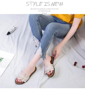 Detailed view of fashionable beige ruffled flat slide sandals for women in a lifestyle scene