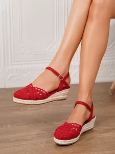 Detalle macro de sandalias de cuña tipo alpargata de ganchillo rojo con hebilla