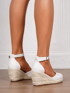 Detail view of white wedge sandals with braided jute heels and ankle straps for summer.