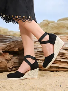 Primer plano de sandalias con cuña negras con suela de paja trenzada y correas