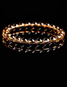 Close-up of a high-clarity yellow citrine crystal beaded bracelet on black reflective surface