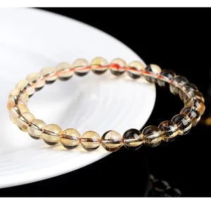 Close-up of natural yellow citrine bead bracelet on white ceramic plate.