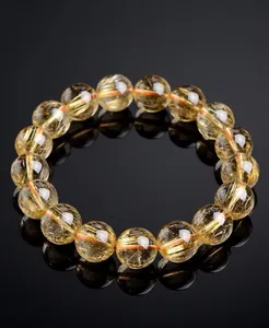 Detailed macro shot of natural yellow citrine crystal beads on a bracelet with reflection.